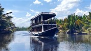 Poznávací zájezd - Plavba pralesem Kalimantanu - Tradiční hausbót na řece obklopené tropickou vegetací.