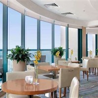 Hilton Dubai Jumeirah Beach - Elegantní restaurace hotelu Hilton Dubai Jumeirah Beach s velkými okny a výhledem na okolí resortu. - www.marco-polo.cz