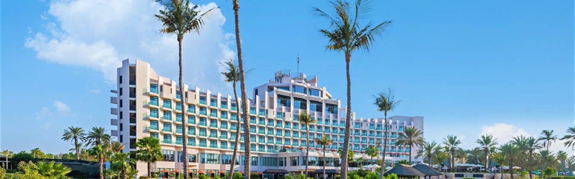Marco Polo - JA The Resort JA Beach Hotel - Exteriér hotelu JA Beach Hotel v resortu JA The Resort v oblasti Jebel Ali v Dubaji s tropickou zahradou a bazénem.