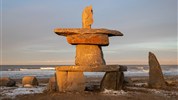 Tundra Buggy Lodge s Městem a Polárnimi Medvědy - Inukshuk při západu slunce v Churchillu připomíná symboliku severní Kanady a propojení krajiny s původními kulturami. Prohlídka Churchillu a okolí doplňuje medvědí program o místní historii, kulturu a atmosféru odlehlého města u Hudsonova zálivu.