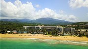 Wyndham Grand Rio Mar - Pohled na plážový resort Wyndham Grand Rio Mar v oblasti Río Grande s oceánem, palmami a zelenými svahy v pozadí.