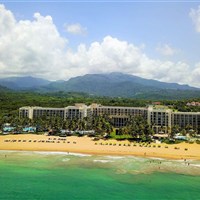 Wyndham Grand Rio Mar - Pohled na plážový resort Wyndham Grand Rio Mar v oblasti Río Grande s oceánem, palmami a zelenými svahy v pozadí. - www.marco-polo.cz